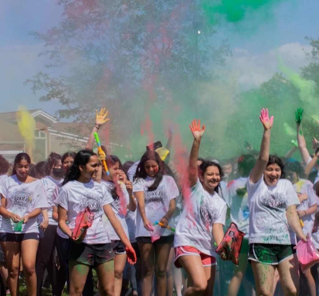 Students throw colorful powder in teh air for a Holi celebration